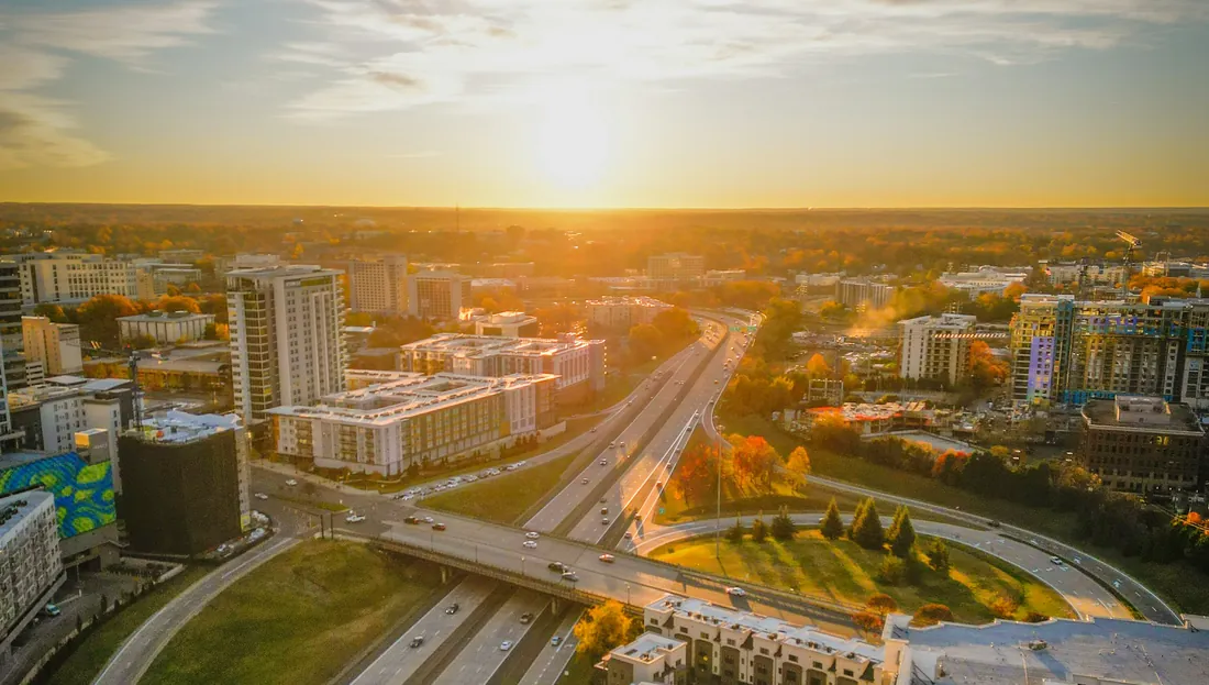 Aerial view of Charlotte at sunrise, with a highway interchange and apartment buildings
