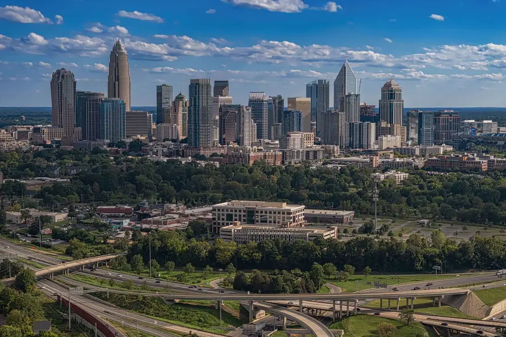Charlotte skyline above tree-lined parkland and a highway interchange